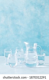 Water In Glasses And A Glass Pitcher On A Table On Blue Background