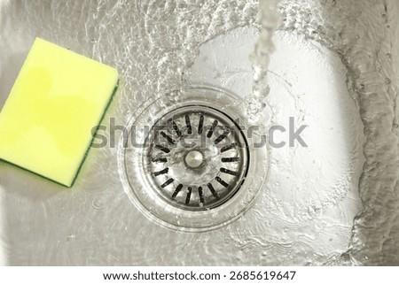 Water going down drain and sponge in sink, top view