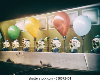 Water Gun Clown Carnival Game Balloons Retro. Classic Water Gun Clown Balloon Carnival Game. Old, Aged Clown Heads. Squirting And Balloons Inflating. Edited With A Vintage Film Effect.