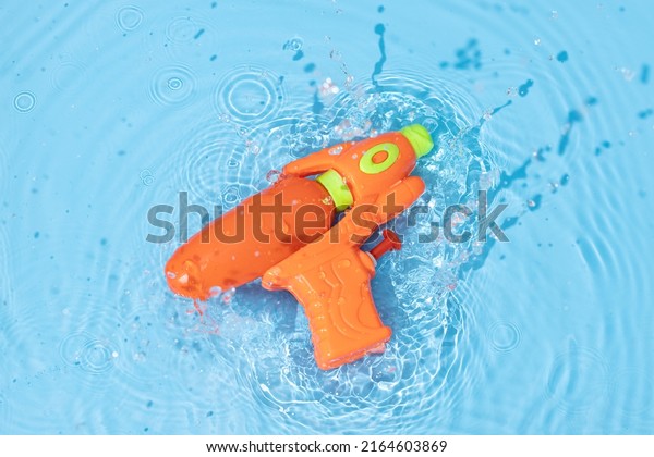 Water gun toy splashing on blue water surface.\
Fun, leisure summertime\
background