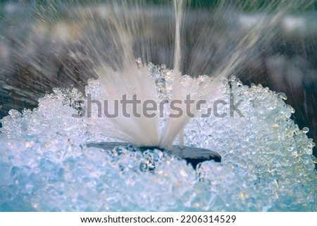 Water gushes (leaky cap) from an artesian well enclosed in a pipe (bored tube well) in the middle of a mountainous area. Winter and freezing of ice and snow on the bush