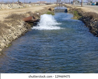 Water gushes from underground pipe into a Central California irrigation canal