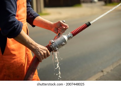 Water hose. The flow of water from the pipe. A man holds a fire hose.