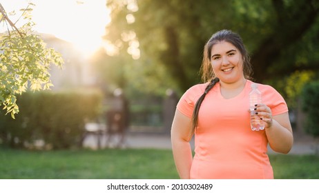 Water Hydration. Weight Loss Diet. Body Positive. Healthy Lifestyle. Happy Smiling Young Obese Overweight Woman Holding Bottle With Clear Liquid In Defocused Empty Space Park.