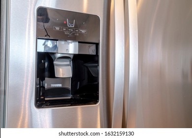 Water And Ice Dispenser On The Shiny Door Of A Refrigerator Inside A Home