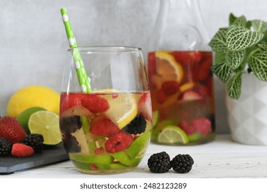 Water infused with berries and citrus slices or summer berry sangria - drink in glass with carafe in background - Powered by Shutterstock