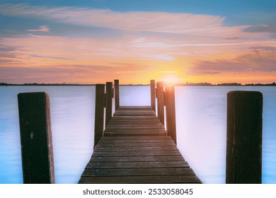 Water and lake with wooden jetty (pier) with the setting sun on the horizon and a cloudscape sky in beautiful colors. Countryside landscapes of Netherlands, Giethoorn - Powered by Shutterstock