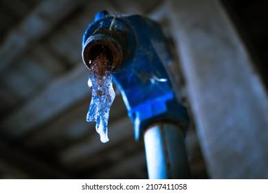 Water Leaking Out Of A Pitcher Pump Has Frozen Over, Forming A Dirty, Crystalline Structure