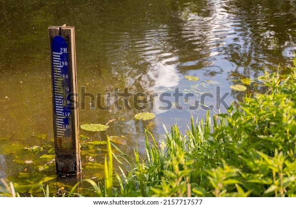 Water level depth meter, gauge or staff gauge,\
in the river. Extreme low water in river. Global warming. Shortage\
or lack of water due to hot temperatures. Government measurements.\
Crisis and climate.
