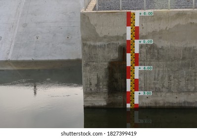 Water Level Indicator In Red And White On Reinforcement Concrete Wall Of Watergate For Water Management Support Agriculture. Concept Of Water Level Measurement, Water Management, Saving Environment.