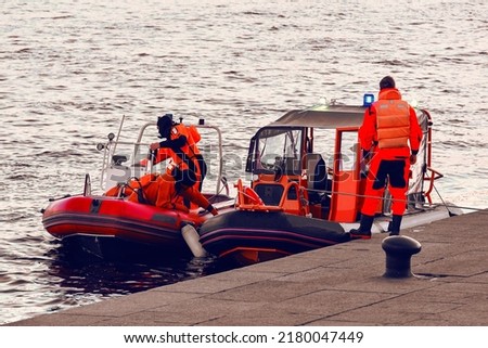Water lifeguards on the pier. Motor boats with rescuers moored to the shore. Rescue inflatable boats on the water.