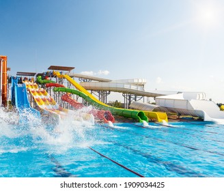 Water park, bright multi-colored slides with a pool. A water park without people on a summer day. - Shutterstock ID 1909034425