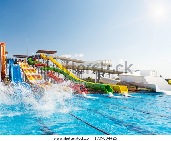 Water park, bright multi-colored\
slides with a pool. A water park without people on a summer\
day.