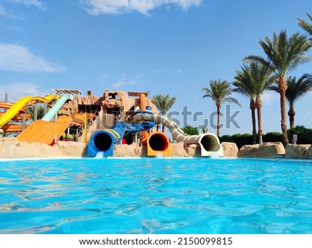 Water park with colorful slides and pools. Water slides and palm trees in a aqua park without people.