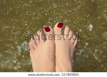 Water pedicure covered with red and gold lacquer on the feet in the pond.