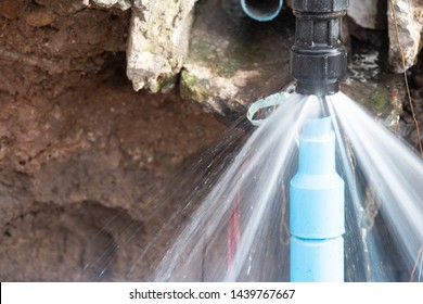 Water pipe break .Exposing a burst water main, focused on the spraying water and the pipe. 
