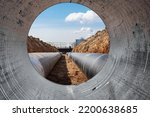 Water pipes for drinking water supply lie on the construction site. View from a large concrete pipe. Preparation for earthworks for laying an underground pipeline. Modern water supply systems