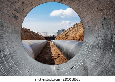 Water pipes for drinking water supply lie on the construction site. View from a large concrete pipe. Preparation for earthworks for laying an underground pipeline. Modern water supply systems