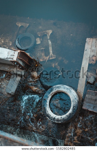 Water pollution with congestion in the riverbed.\
Urban garbage global problem. Environmental conservation. Global\
pollution vertical background. Environmental problem. Water blocked\
by tires debris.