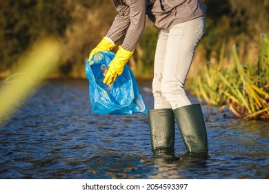 Water Pollution. Environmental Volunteer Cleaning River From Used  Plastic Bottles And Garbage