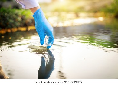 Water Pollution In The Pond, River, Lake, Sea Concept. Scientist Takes Samples Of Factory Wastewater In A Test Tube. Close Up The Hand.