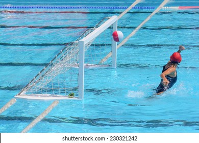 A water polo goalkeeper misses the ball going into the net of the goal.