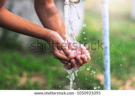 water pouring in faucet  on hand child in park