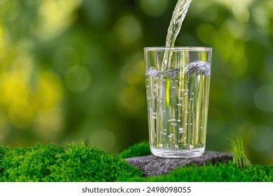 water pouring into glass on stone with moss