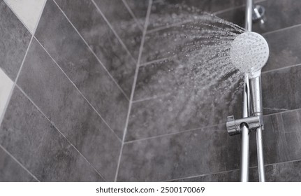 Water is pouring from the shower head into the shower room, close-up. Refreshing shower, cleanliness and hygiene