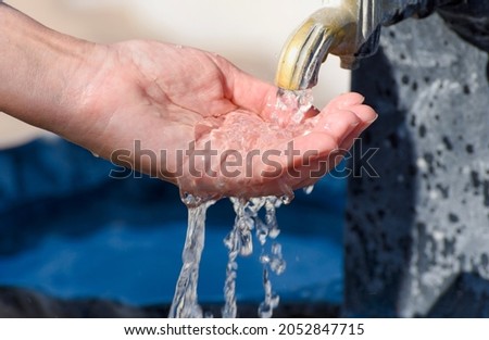 Water pours into the hand from a drinking fountain. Selective focus.