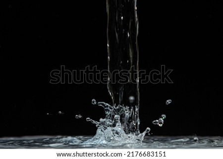 Water pours onto the surface of the water on a black background. Clean drinking water.
