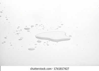 Water puddles and droplets on white reflective surface. Frontal view and deep focus.