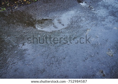 water puddles with raindrops and water circles on wet asphalt road