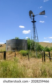 A Water Pump Windmill With A Water Storage Tank In The California Central Valley In A Hilly Grassland