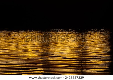 The water is reflecting the sun's light, creating a beautiful and serene scene. Concept of calm and tranquility, as the water's surface is still and undisturbed. The golden hues of the water