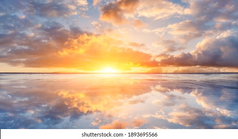 Water reflection and sky sunset clouds on asphalt road.