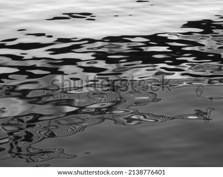 Water reflex background. Abstract reflection and abstract inspection elements in water. City elements distorted in the river. Rippled water texture. Black and white water surface. Layout, template.