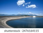 Water reservoir dam holding back water with mountains in background.