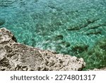 Water ripples in a calm sea with rocks beneath