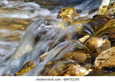 Water Rolling Over Yellow Stones In A Wild River