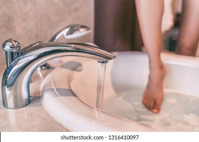Water running bath woman dipping toes in hot bathtub relaxing time at home . Luxury cozy lifestyle people.
