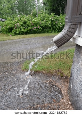 Water running down from a drain pipe when it`  s raining heavily.