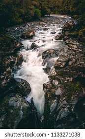 Water Running Through Stream Over Dark Rocks From Water Fall