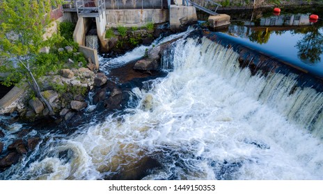 Water Rushing Over Dam Near Small Power Plant