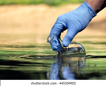 Water sample. Hand in glove collects water to explore. Concept - water purity analysis, environment, ecology. Water testing for infections, permission to swim