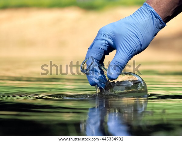 Water sample. Hand in
glove collects water to explore. Concept - water purity analysis,
environment, ecology. Water testing for infections, permission to
swim