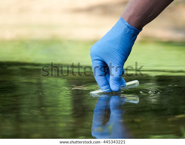Water sample. Hand in\
glove collects water in a test tube. Concept - water purity\
analysis, environment, ecology. Water testing for infections,\
permission to swim