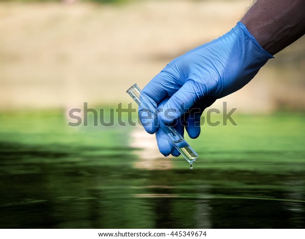 Water sample. Hand in\
glove collects water in a test tube. Concept - water purity\
analysis, environment, ecology. Water testing for infections,\
permission to swim