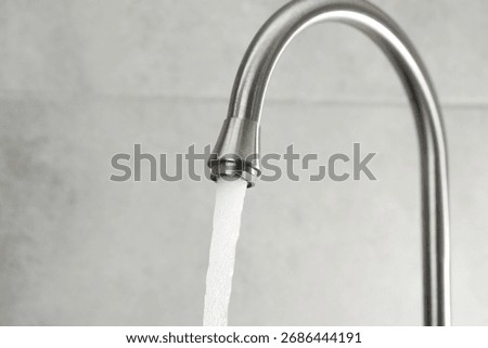 Water saving concept. Stream of water flowing from tap indoors, closeup