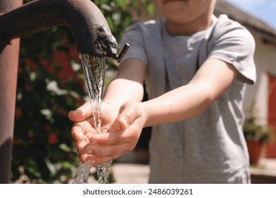 Water scarcity. Little boy drawing water with hands from tap outdoors, closeup - Powered by Shutterstock